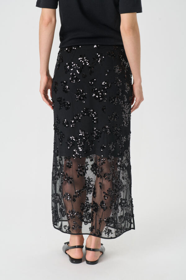 Black sequin skirt worn by a person on a white background