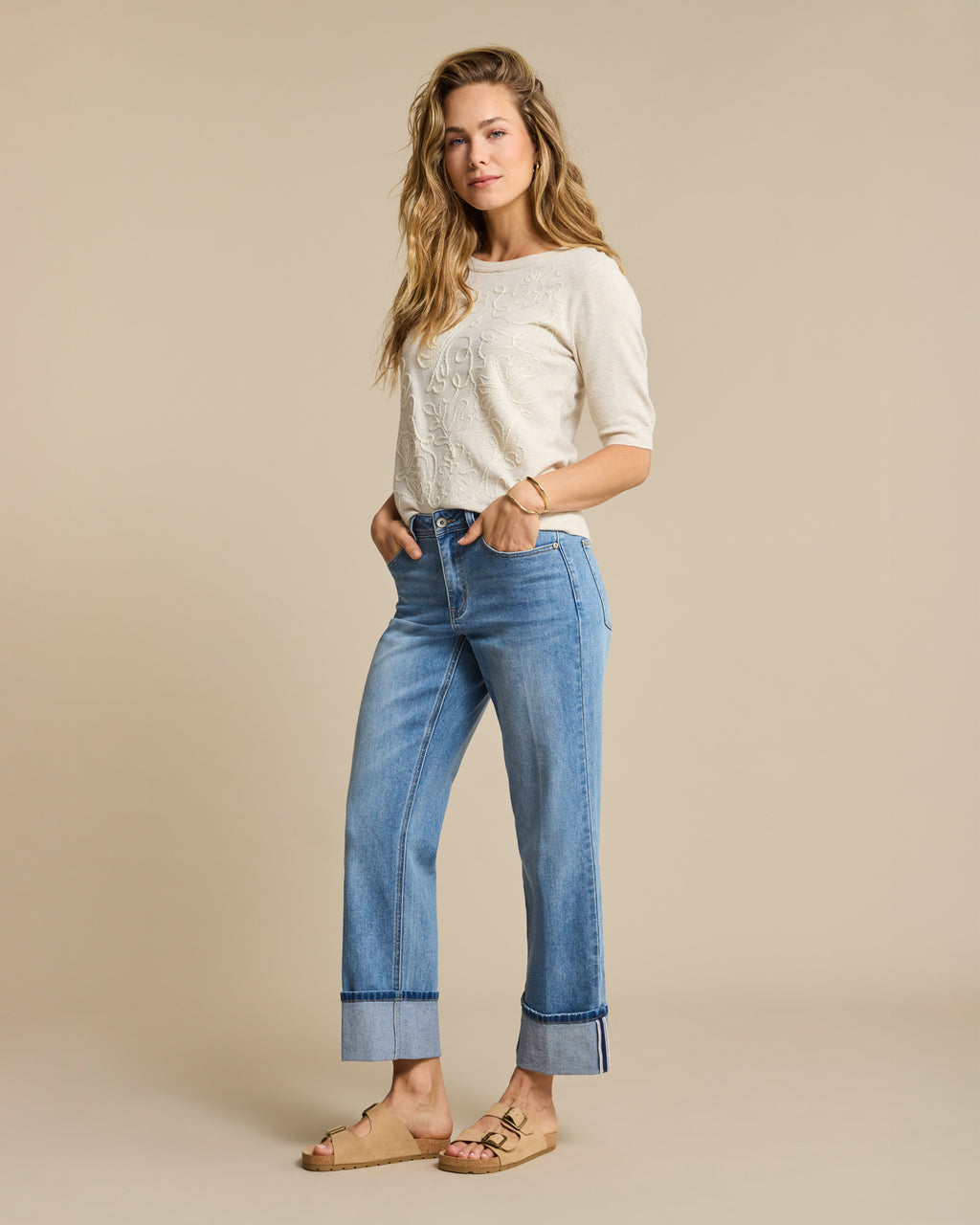 Red Button - Woman wearing a white top and blue jeans against a beige background